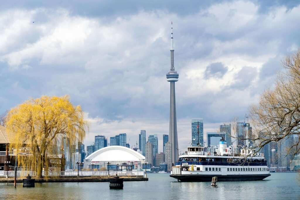 Ferry crossing Toronto harbor with passengers viewing the downtown skyline and CN Tower reflected on calm Lake Ontario waters in May