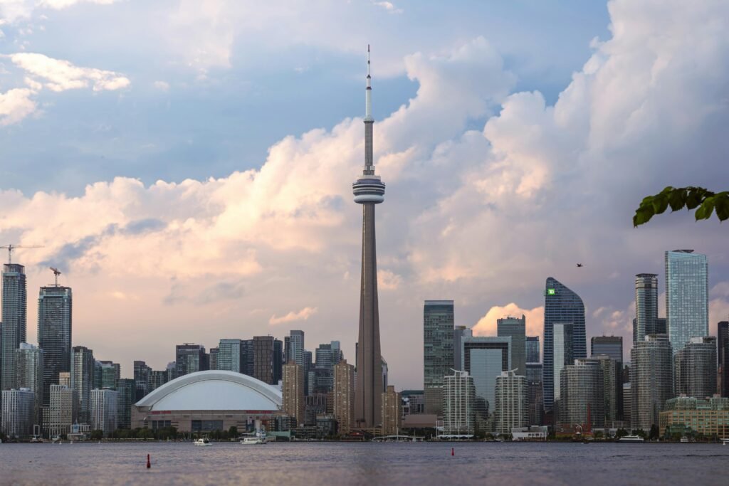 Low-angle view of CN Tower at dusk with Ripley's Aquarium and Rogers 
Centre visible along Toronto's waterfront at sunset