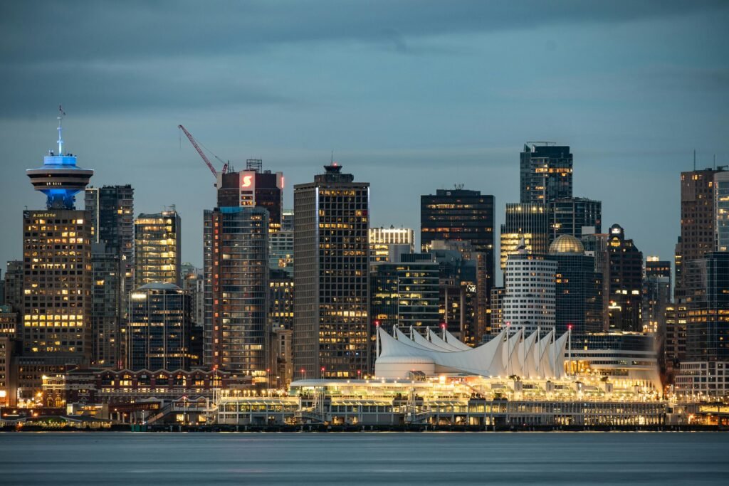 Vancouver skyline at dusk with snow-capped North Shore mountains reflected in Burrard Inlet at golden hour